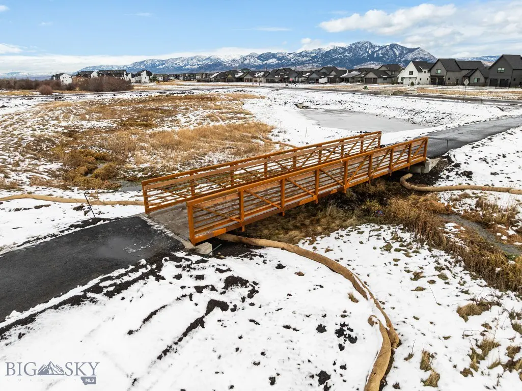 Wooden bridge over creek in Meadow Bridge with snowy ground and mountains
